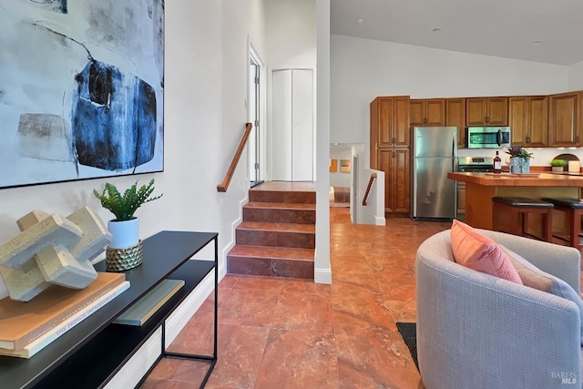 kitchen featuring stainless steel appliances, lofted ceiling, brown cabinetry, and wood counters