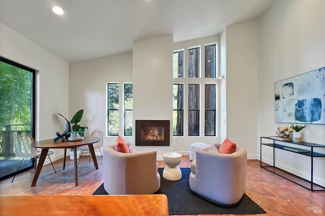 living area with high vaulted ceiling, a lit fireplace, baseboards, and recessed lighting