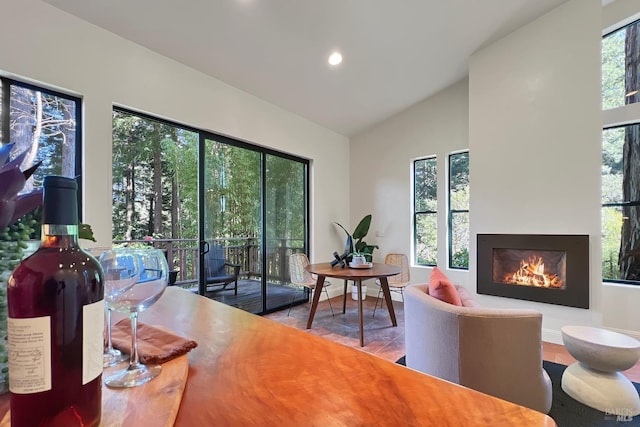 interior space featuring lofted ceiling, a warm lit fireplace, baseboards, and recessed lighting