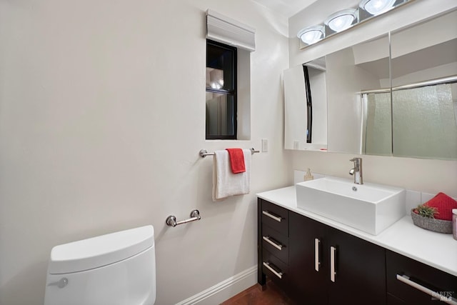 full bath featuring a shower with door, vanity, toilet, and baseboards