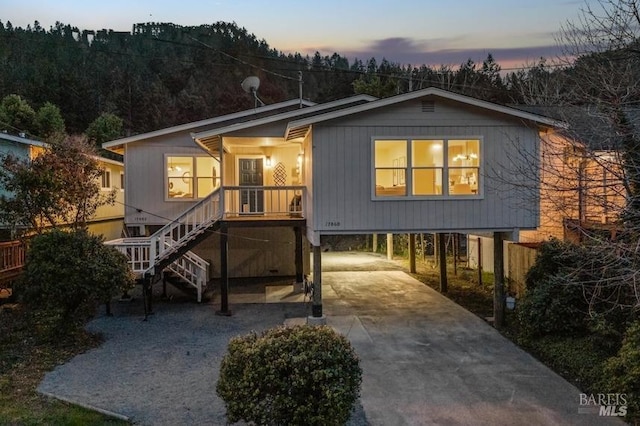 view of front of house with covered porch, stairs, a carport, and concrete driveway