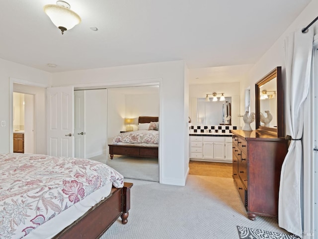 bedroom featuring light carpet, a closet, and ensuite bathroom