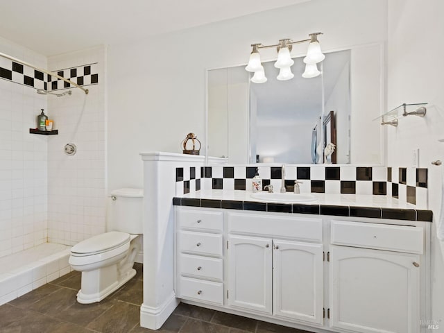 full bath with tasteful backsplash, tiled shower, vanity, and toilet