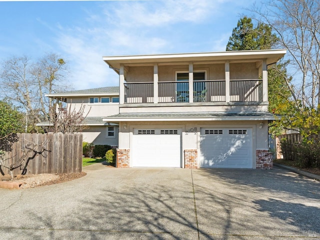 view of property with brick siding, stucco siding, concrete driveway, an attached garage, and fence