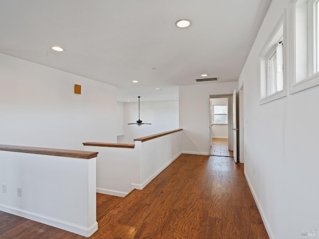 corridor featuring recessed lighting, wood finished floors, visible vents, baseboards, and an upstairs landing