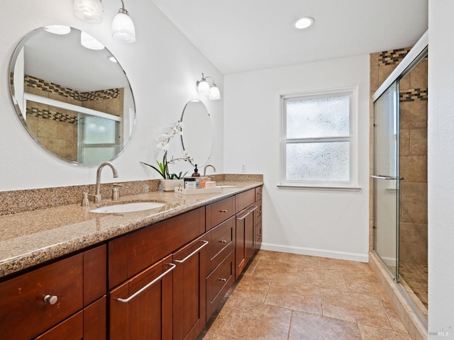 bathroom with double vanity, a stall shower, baseboards, and a sink