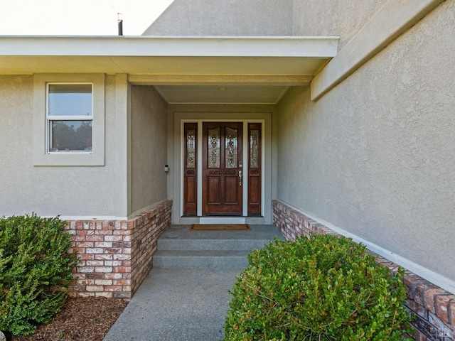 entrance to property with brick siding and stucco siding