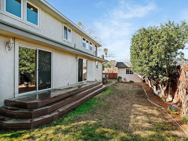 view of yard with fence, a deck, and an outdoor structure