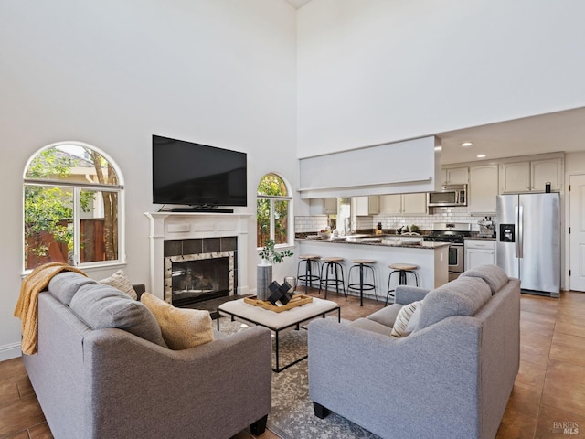 living room featuring a high ceiling, a tiled fireplace, and tile patterned flooring