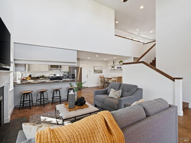 living area featuring recessed lighting, a fireplace, a high ceiling, and stairs