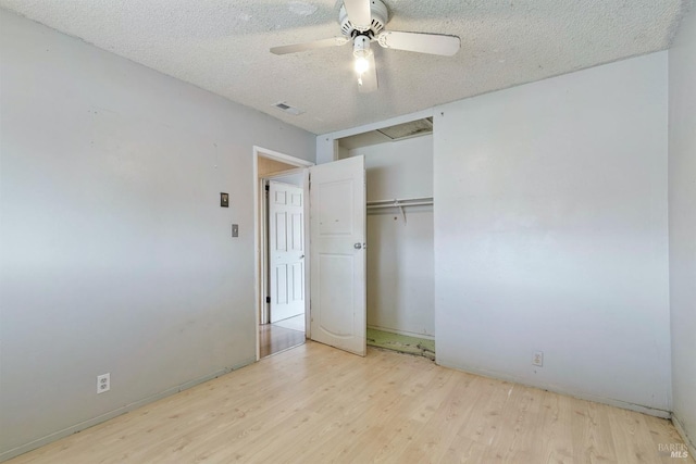 unfurnished bedroom with a textured ceiling, wood finished floors, visible vents, a ceiling fan, and a closet