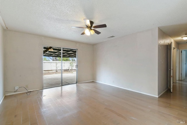 spare room featuring baseboards, visible vents, a ceiling fan, wood finished floors, and a textured ceiling