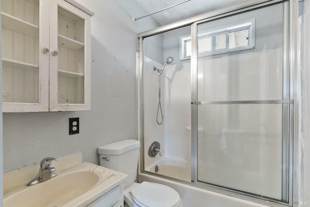 bathroom featuring toilet, bath / shower combo with glass door, and vanity