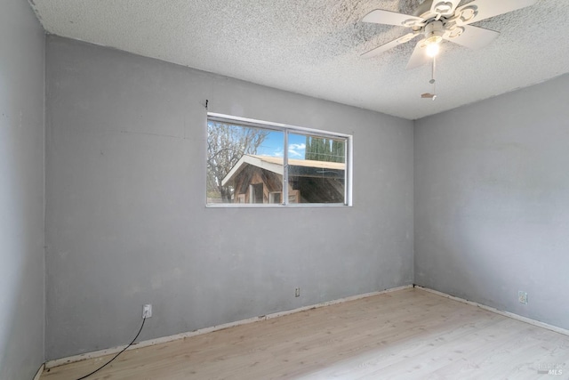 spare room featuring a textured ceiling, wood finished floors, and a ceiling fan