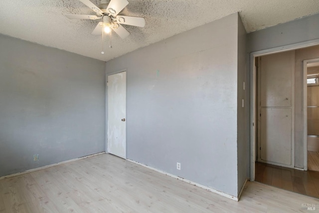 spare room featuring ceiling fan, a textured ceiling, baseboards, and wood finished floors