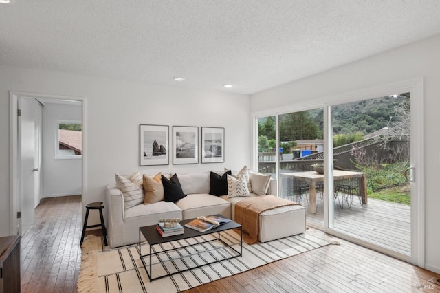 living area with light wood-style floors, a textured ceiling, and recessed lighting