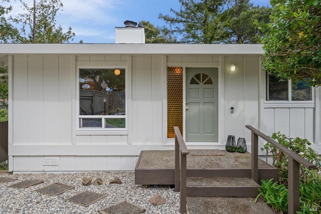 entrance to property featuring a chimney and board and batten siding