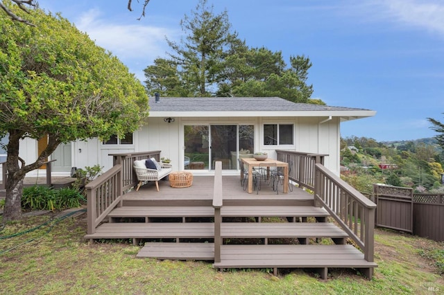 back of property featuring outdoor dining space, fence, board and batten siding, and a wooden deck