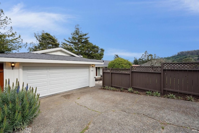 garage featuring driveway and fence