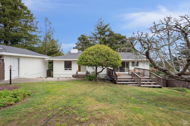 back of house with a yard, a chimney, and a wooden deck