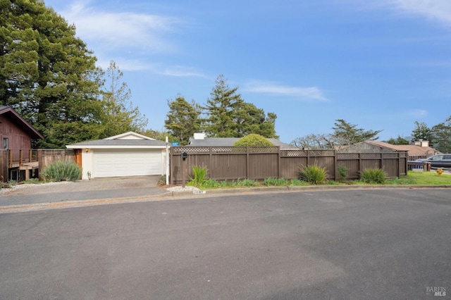 view of front of property with a detached garage, fence, and an outdoor structure