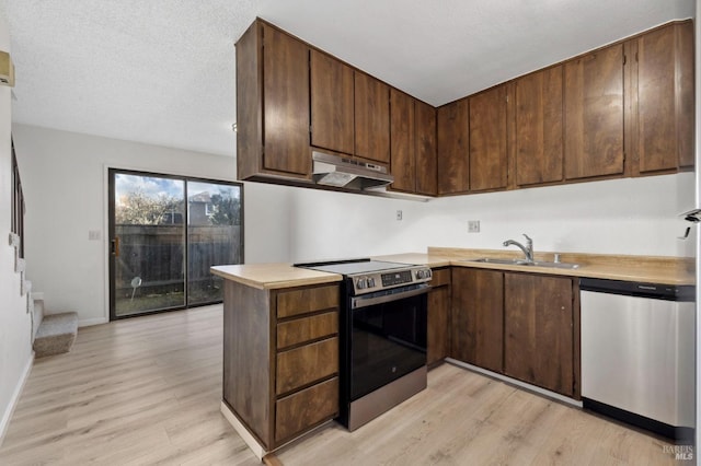 kitchen featuring under cabinet range hood, light wood-style flooring, appliances with stainless steel finishes, and a sink