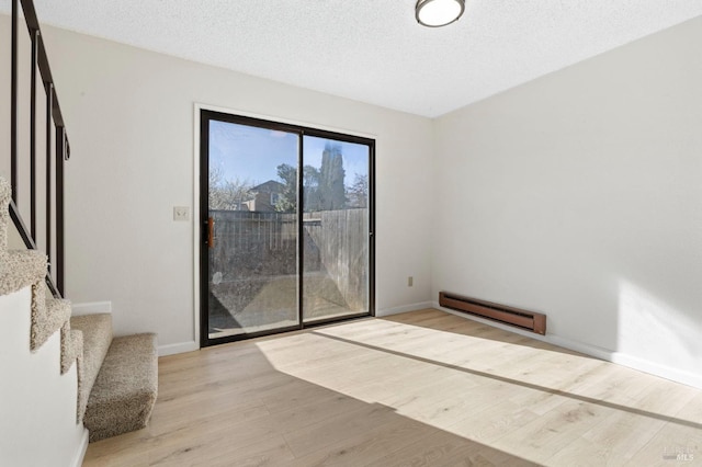 unfurnished room with a baseboard radiator, stairway, a textured ceiling, light wood-type flooring, and baseboards