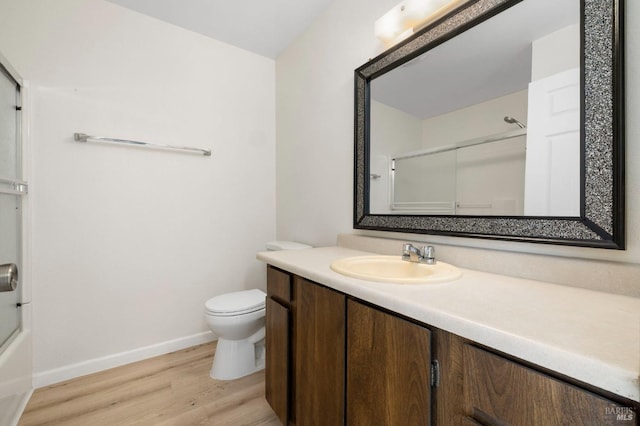 full bath with toilet, shower / bath combination with glass door, wood finished floors, vanity, and baseboards