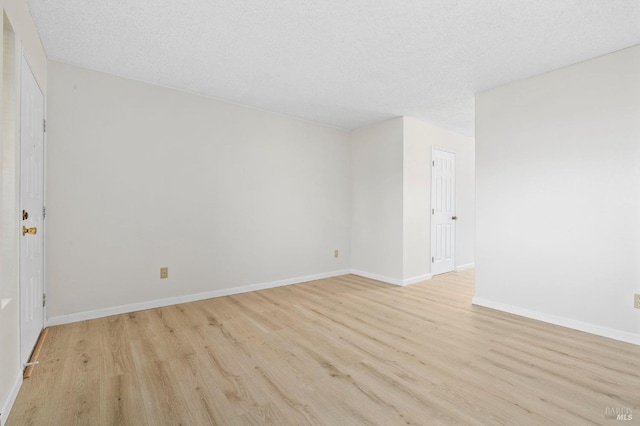 unfurnished room with light wood-style floors, baseboards, and a textured ceiling