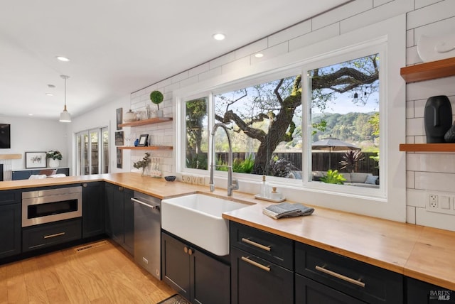 kitchen with dishwasher, wood counters, built in microwave, open shelves, and a sink