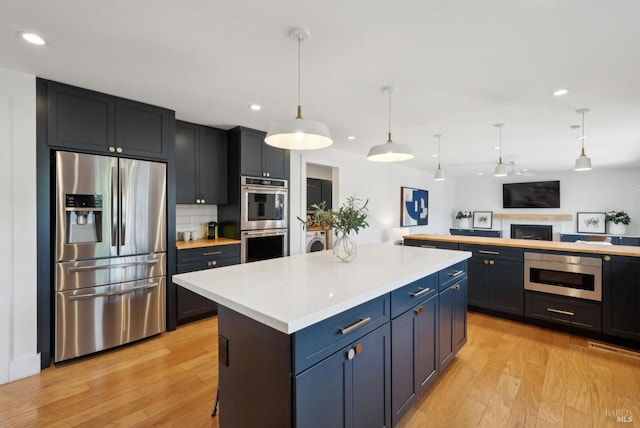 kitchen featuring tasteful backsplash, appliances with stainless steel finishes, washer / clothes dryer, light countertops, and light wood-style floors