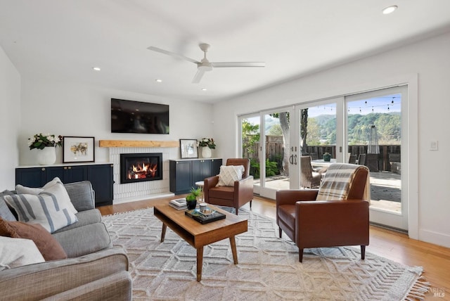 living room featuring french doors, light wood finished floors, recessed lighting, a glass covered fireplace, and baseboards