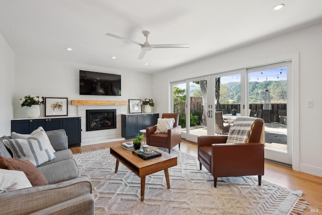 living room with light wood-style floors, a glass covered fireplace, french doors, and recessed lighting