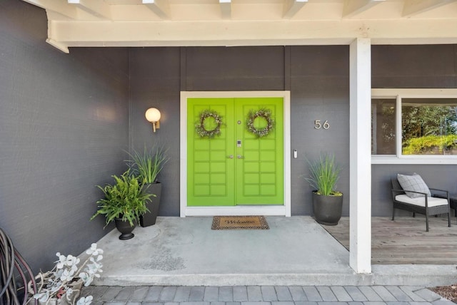 view of exterior entry with a porch and brick siding