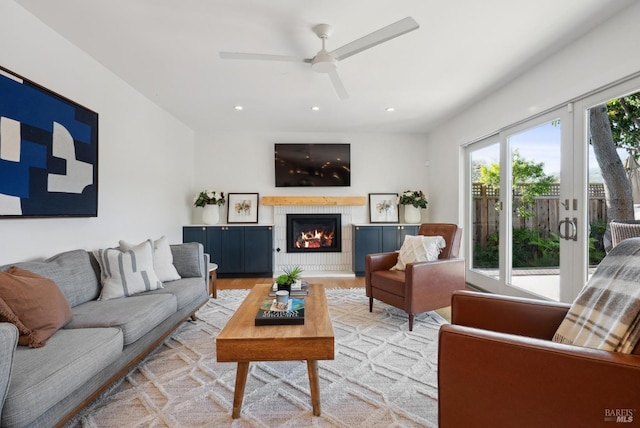 living area featuring light wood finished floors, a ceiling fan, a tile fireplace, french doors, and recessed lighting