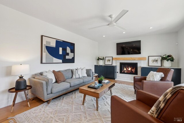 living area featuring baseboards, a glass covered fireplace, ceiling fan, wood finished floors, and recessed lighting