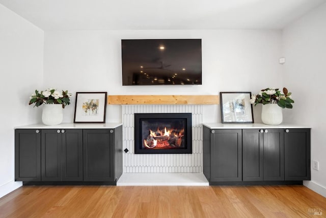 unfurnished living room featuring a warm lit fireplace, baseboards, and wood finished floors