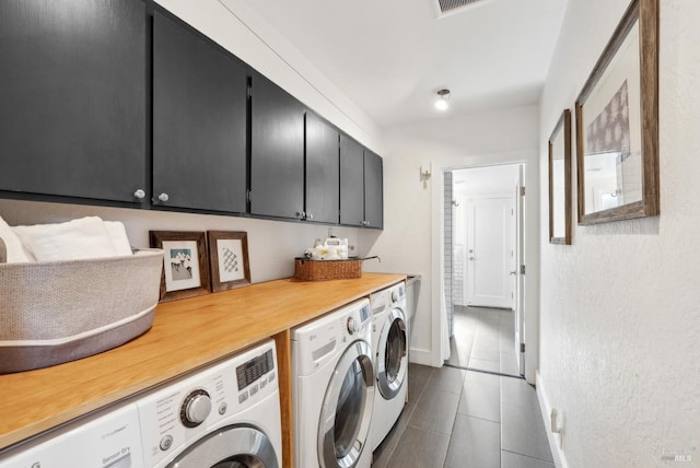 laundry room with dark tile patterned floors, washer and clothes dryer, cabinet space, and baseboards