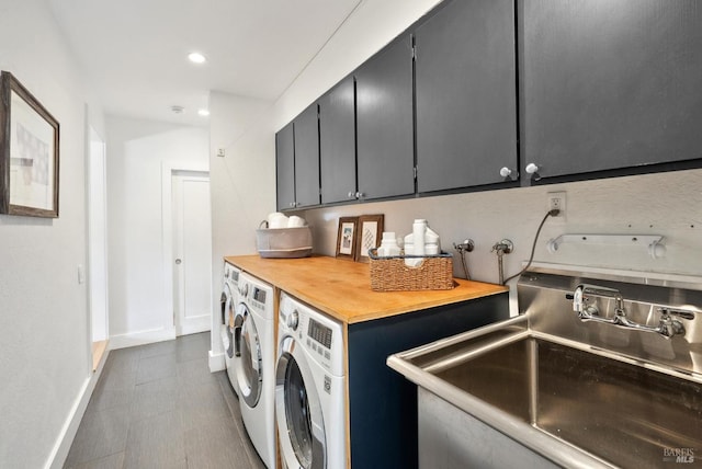 clothes washing area with recessed lighting, cabinet space, washing machine and dryer, a sink, and baseboards