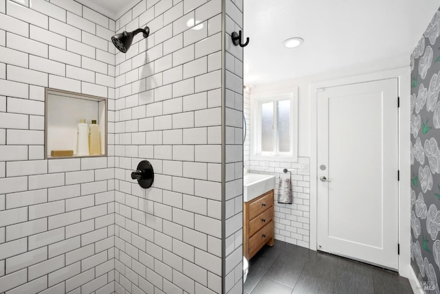 bathroom featuring tile walls, tiled shower, and vanity