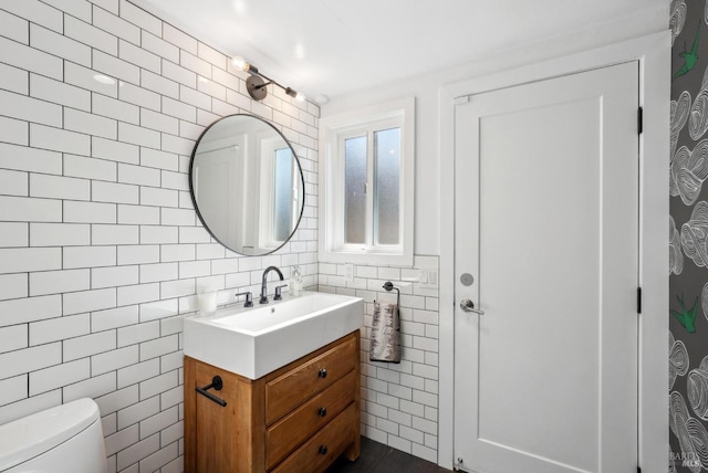 half bath featuring toilet, vanity, and tile walls