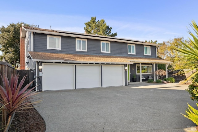 view of front of home with a garage, fence, driveway, and solar panels