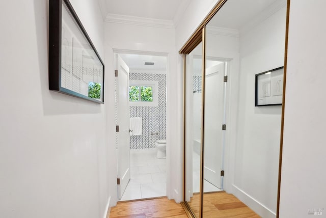 hall with visible vents, ornamental molding, light wood-style flooring, and baseboards