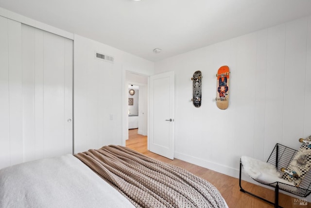 bedroom with a closet, visible vents, and light wood-style flooring