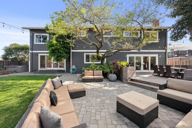 rear view of property with a patio, fence, an outdoor living space, french doors, and a hot tub