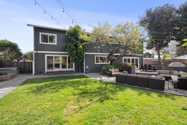 back of house with a yard, a patio, outdoor lounge area, a hot tub, and a fenced backyard