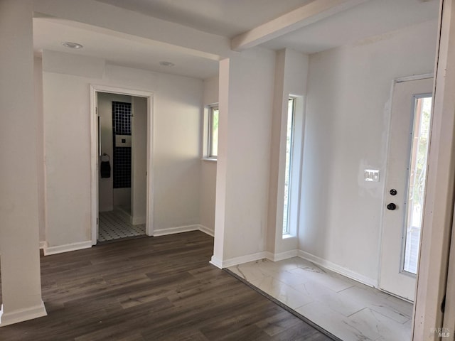 foyer entrance featuring a healthy amount of sunlight, baseboards, beam ceiling, and wood finished floors