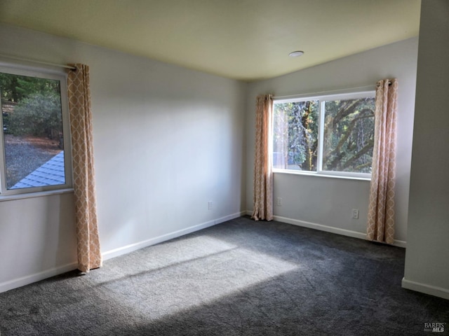 unfurnished room featuring dark carpet and baseboards