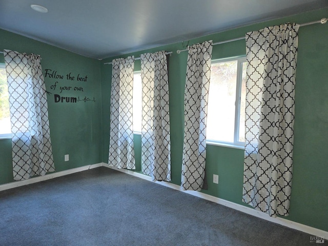 empty room with carpet floors, a healthy amount of sunlight, and baseboards