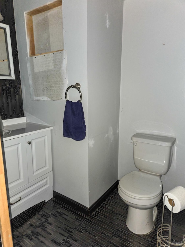 half bath with vanity, wood finished floors, toilet, and baseboards